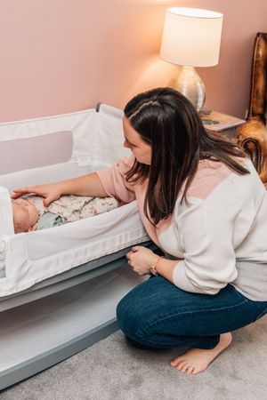 mum putting baby in cot