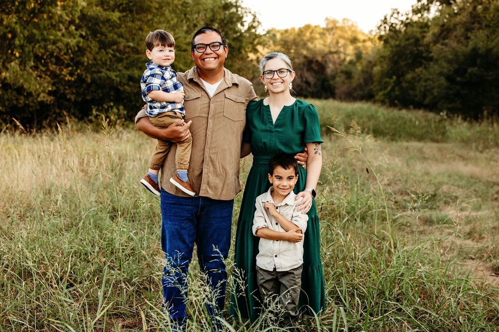 A group stands together in a golden field during sunset creating a warm and intimate outdoor portrait.