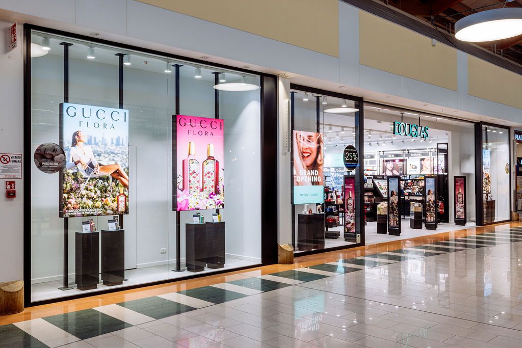 Long retail mall hallway with closed stores, polished floors, and overhead lighting creating reflections.