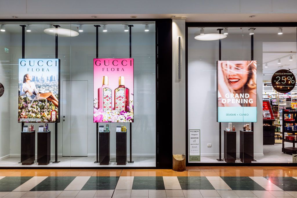 Long shopping mall corridor with illuminated storefronts displaying Gucci and other luxury retail brands.
