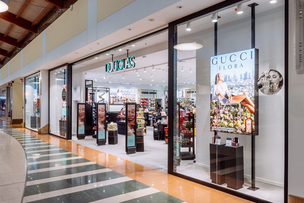 Modern shopping mall interior with luxury retail stores and polished floors under bright lighting.