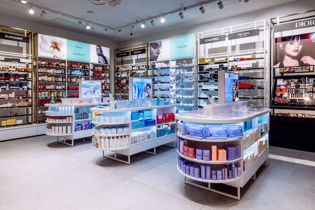 Wide view of a cosmetics store interior showing organized product displays, shelving units and bright lighting.