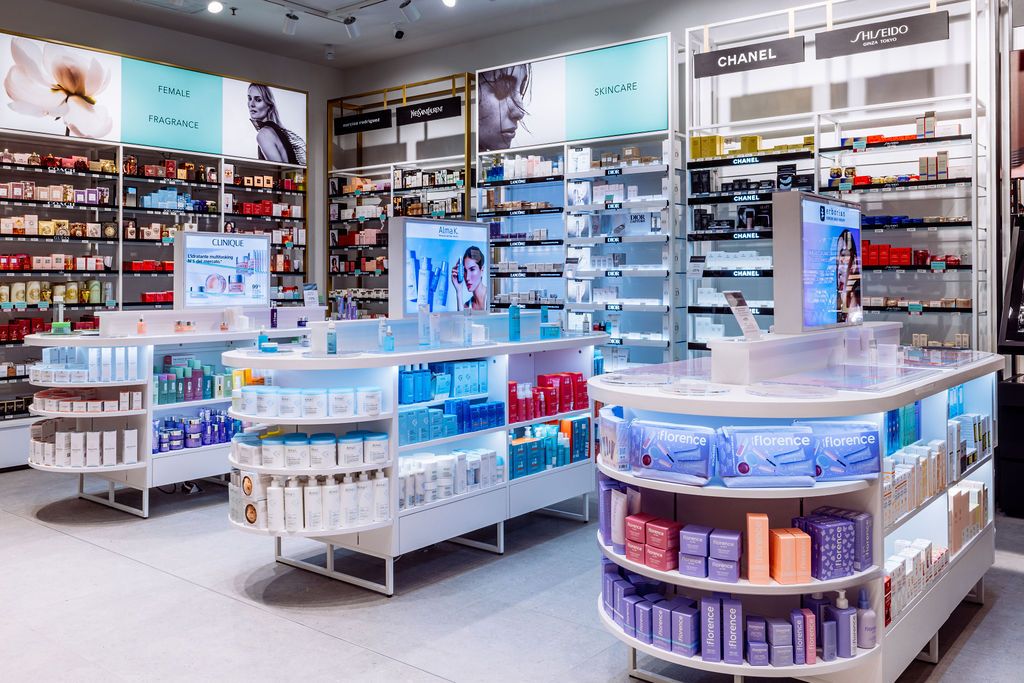 Bright cosmetics department with illuminated display counters and organized skincare products on curved shelves.