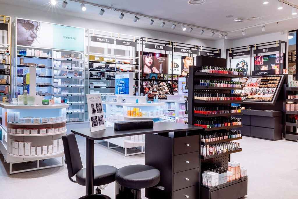 Modern pharmacy interior with clean white shelving displaying beauty and healthcare products under bright lighting.