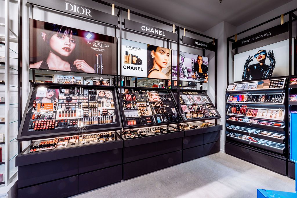 Interior view of a luxury cosmetics store with Dior branding and multiple glass display cases showcasing beauty products.