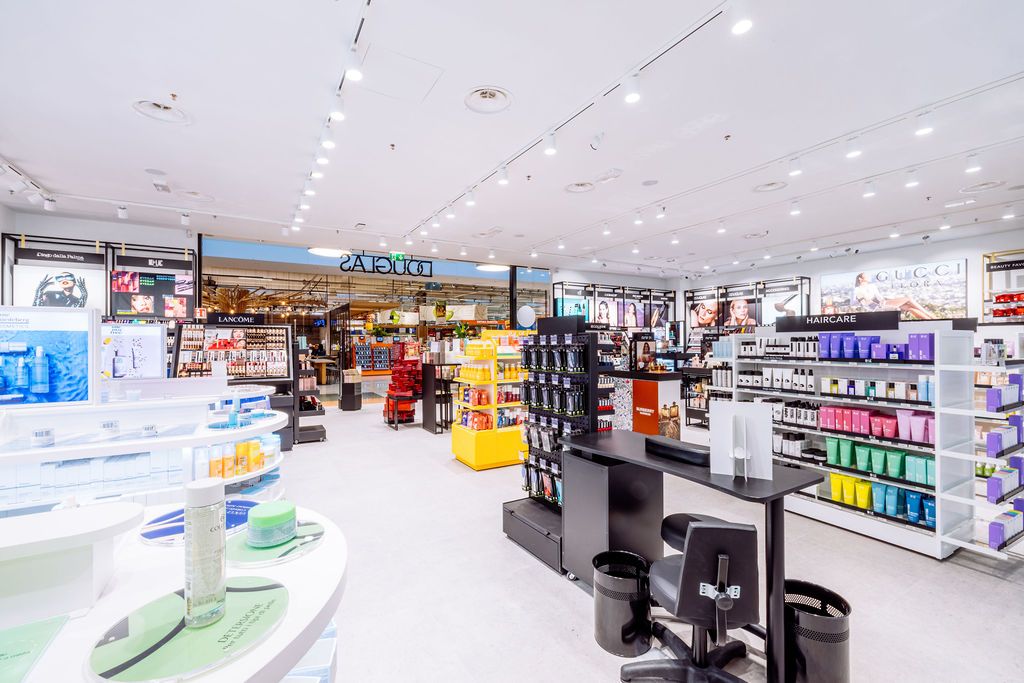 Wide view of a contemporary drugstore interior showing organized aisles and product displays with bright illumination.