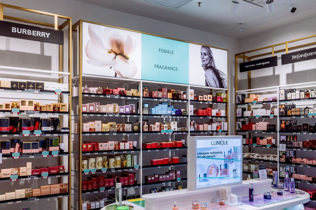 Panoramic view of a modern retail cosmetics store interior with illuminated shelving displays and beauty products.