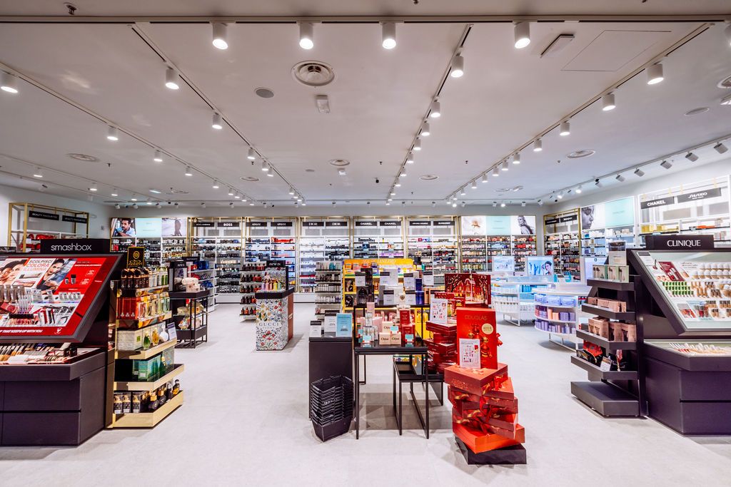 Modern retail store interior with bright lighting, white ceiling, and merchandise displays along the walls.
