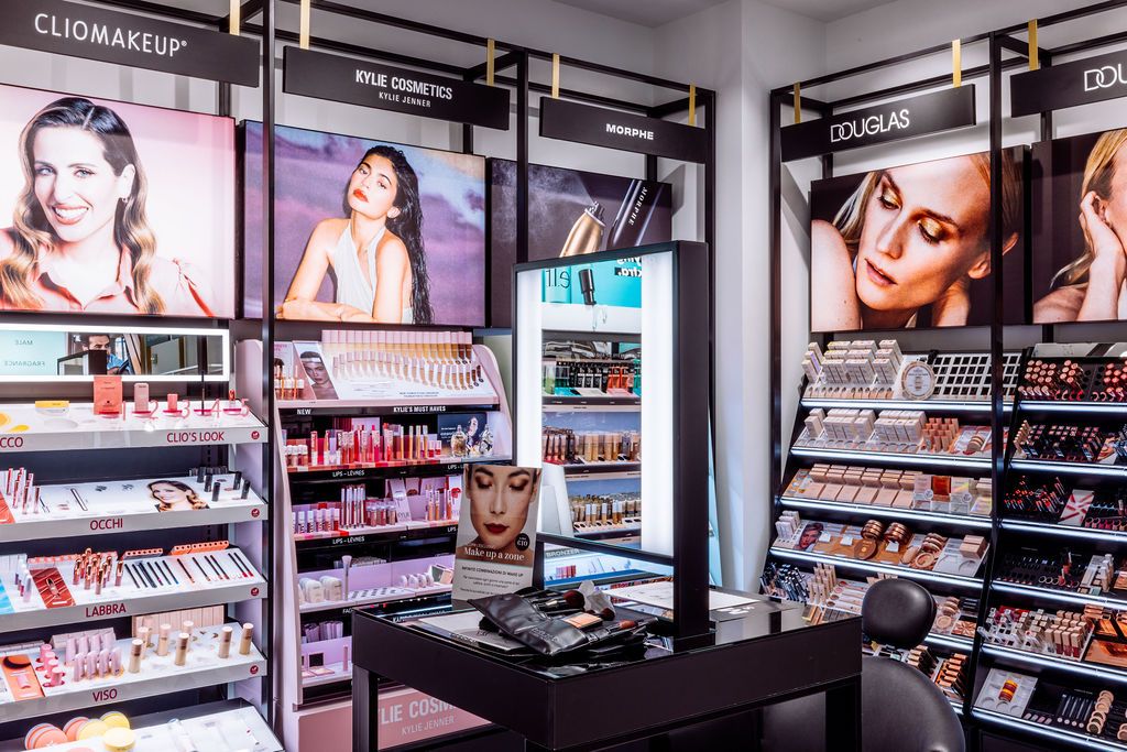 Modern cosmetics retail display with illuminated beauty posters and organized makeup shelves in a sleek store interior.