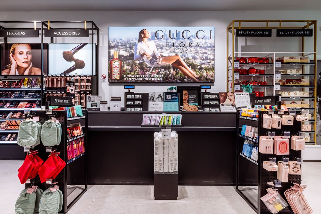Modern retail store interior with black counter, Gucci advertisement display and organized merchandise shelves.