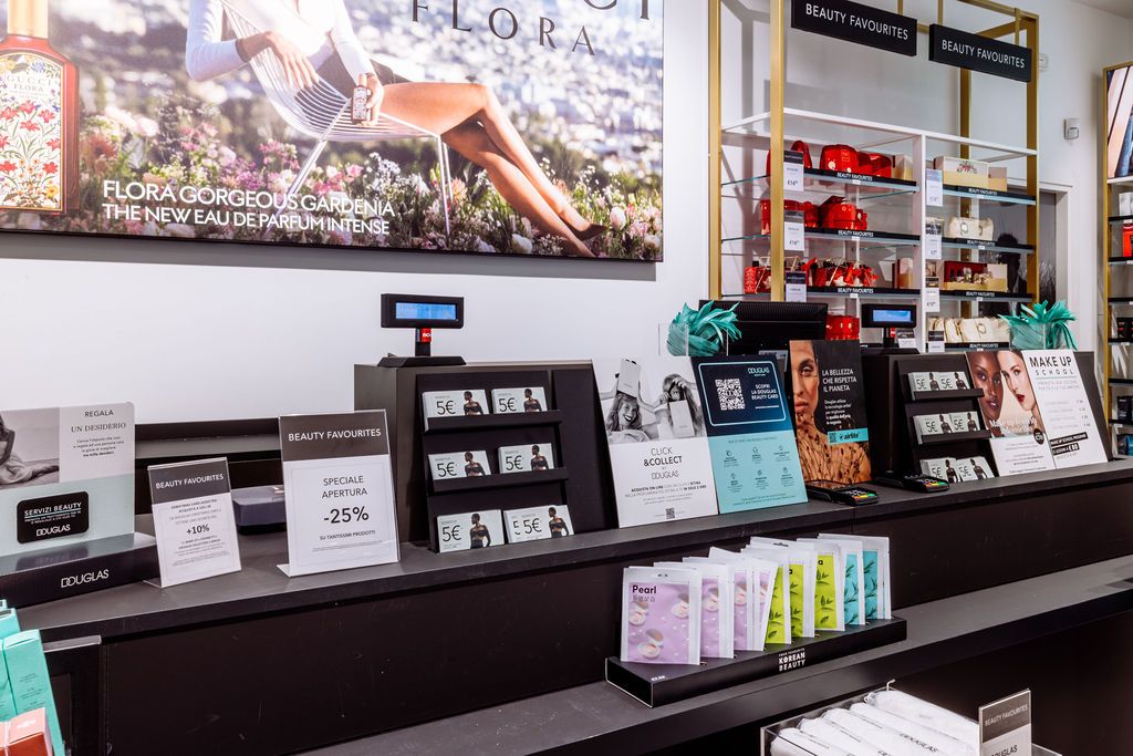 Interior view of a modern retail store with display shelves showing products and a large artistic photograph on the wall.
