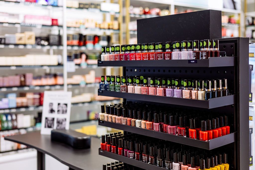 Rows of colorful nail polish bottles displayed on black shelves in a beauty supply store or salon.
