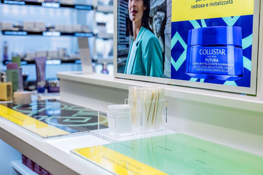 A modern retail display shows various cosmetic and beauty products arranged neatly on illuminated white shelves.