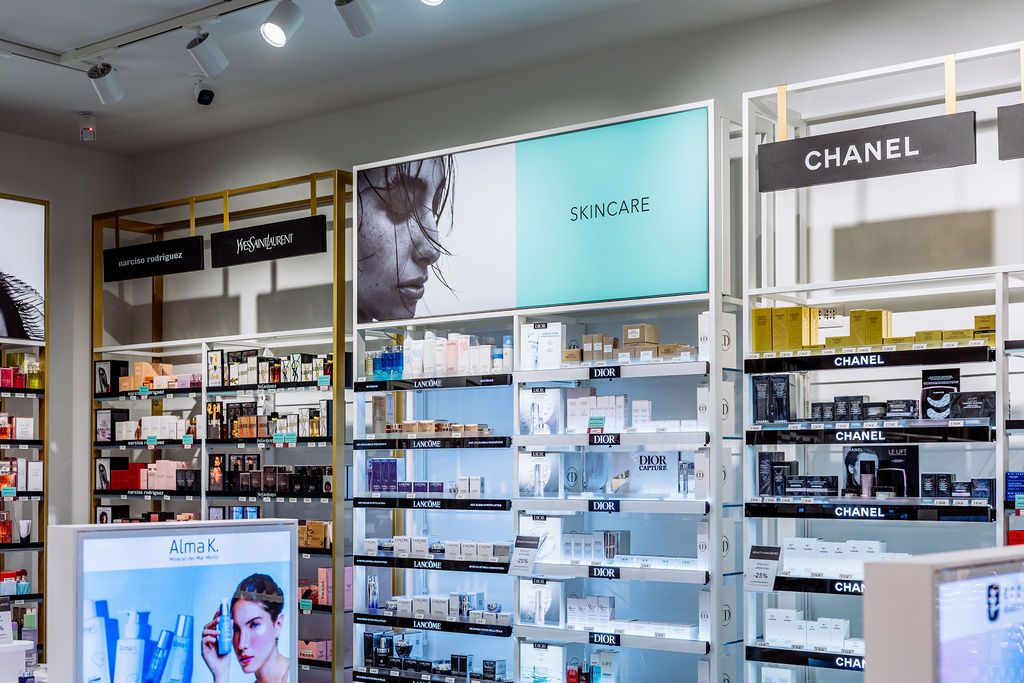Modern retail store interior with bright lighting and glass display cases showing beauty and cosmetics products.