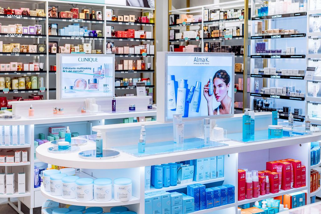 Modern pharmacy interior with white display counters, blue lighting, and shelves stocked with medications and healthcare products.