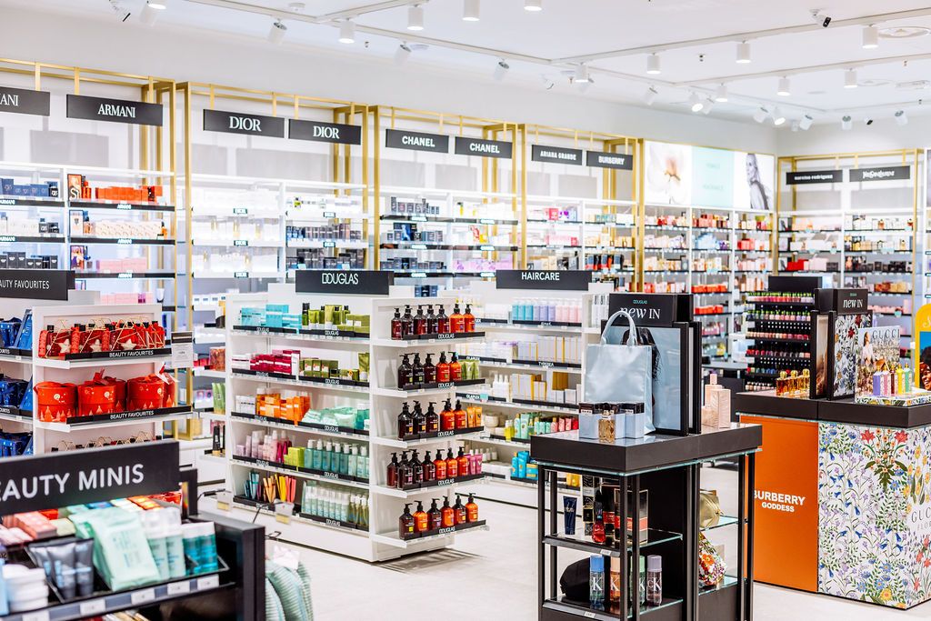 Modern retail store interior with white shelving displays stocked with various products and bright lighting.