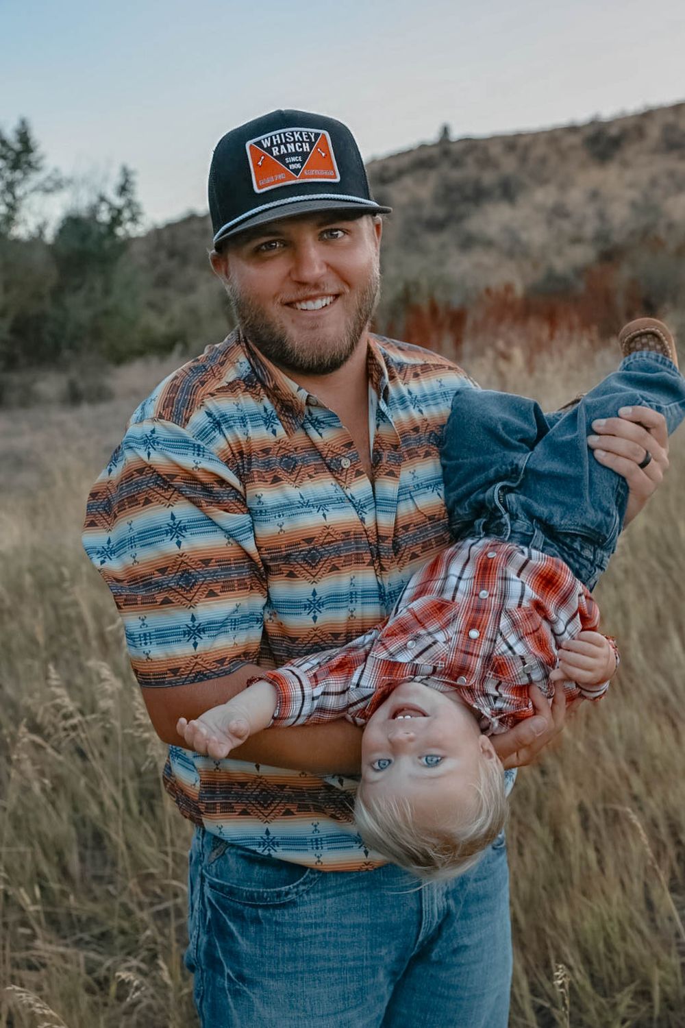 Playful moment captured in a field with casual western-styled clothing.