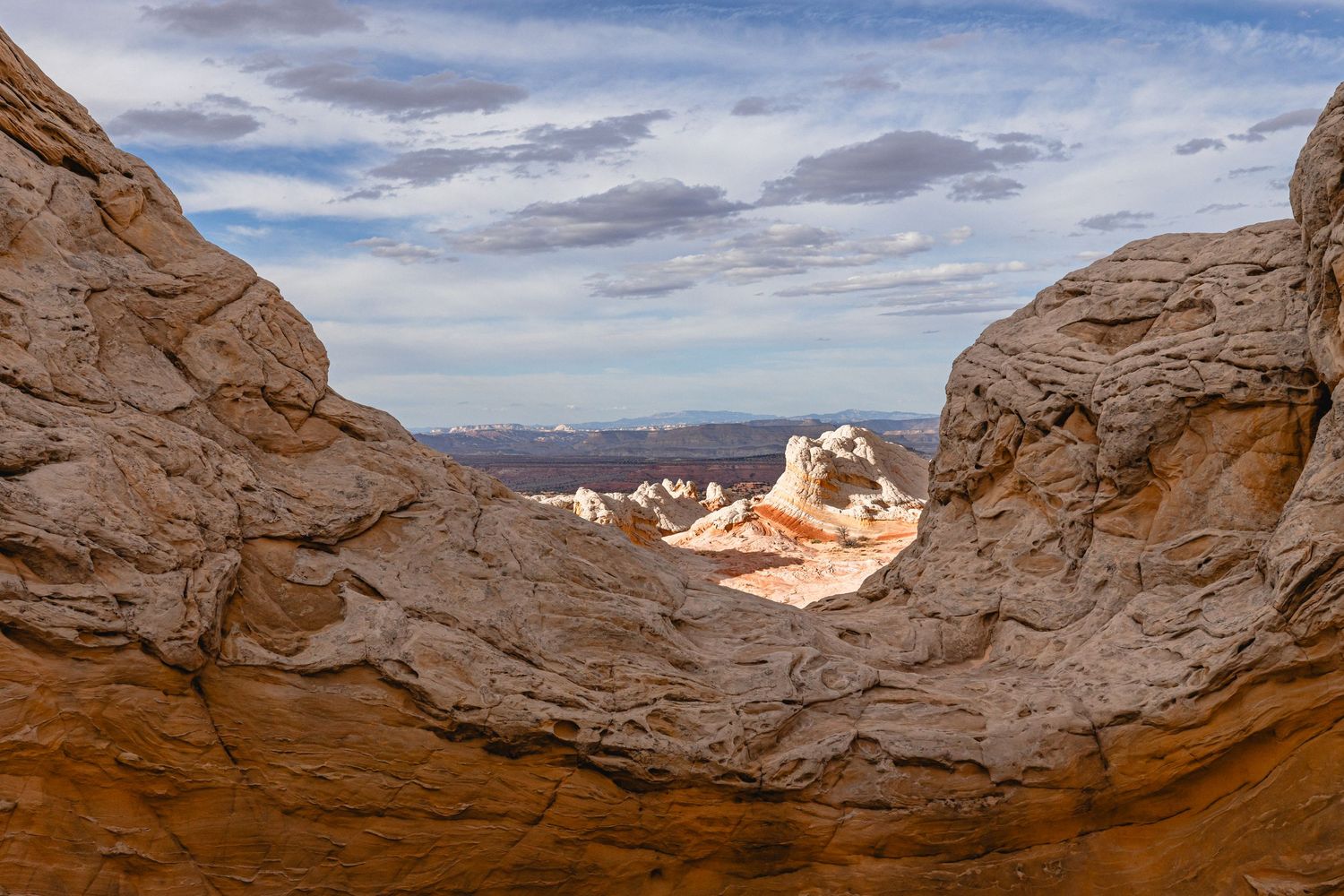 Panoramic view of smooth red sandstone rock formations against bright blue sky in a desert landscape.