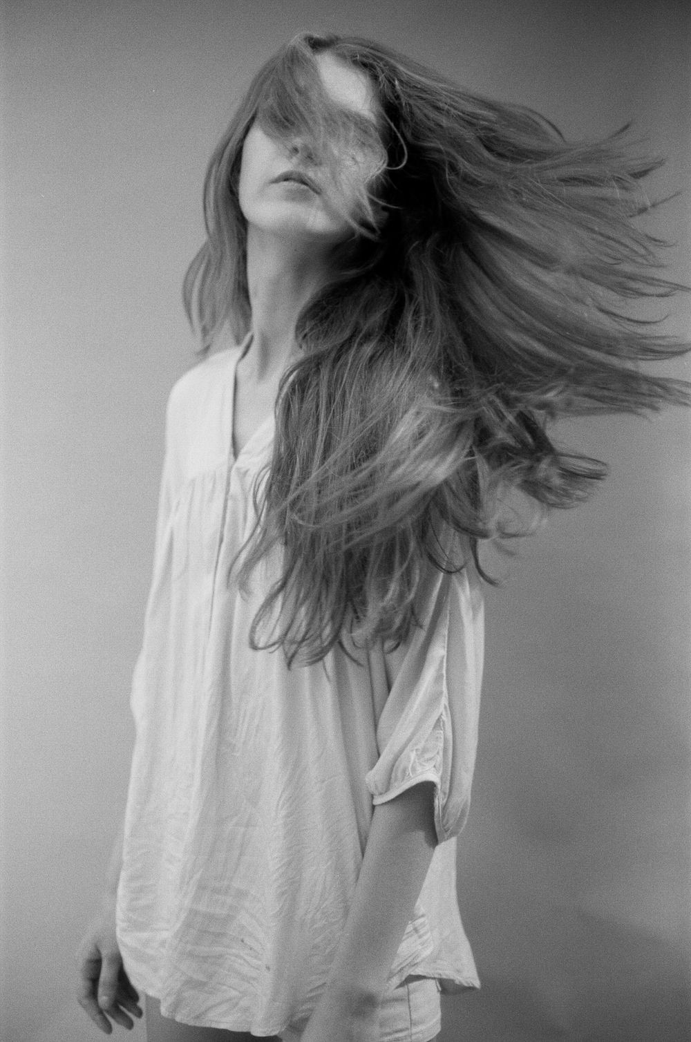 A sequence of black and white photos showing hair in motion as someone tosses their head from side to side.