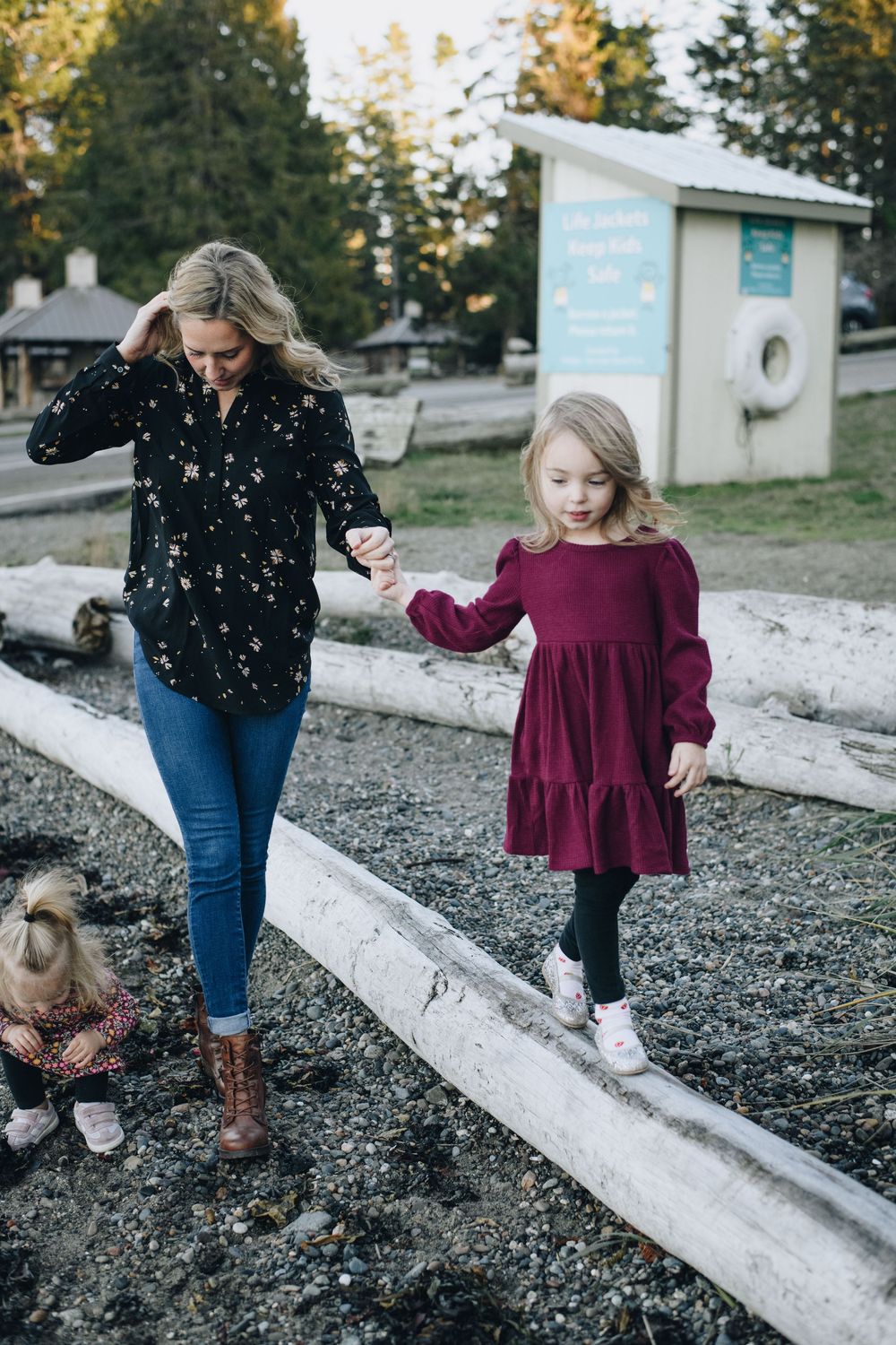 Two people walking carefully along a concrete barrier in a park setting on a fall day.