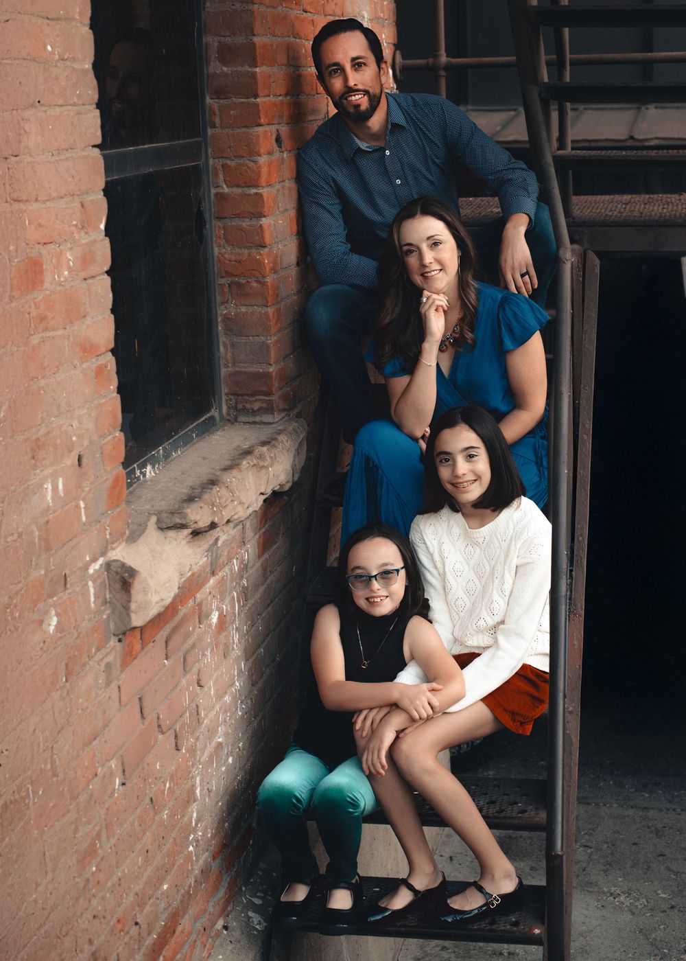 A group sits together in a brick archway alcove, creating a casual family portrait atmosphere.