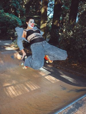 A skateboarder performs a backside flip sequence on a curved concrete ramp in a wooded outdoor setting.