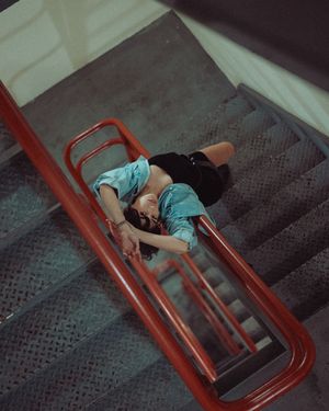 A series of photos showing someone lying on a staircase with dark carpeting and a red railing in dim lighting.