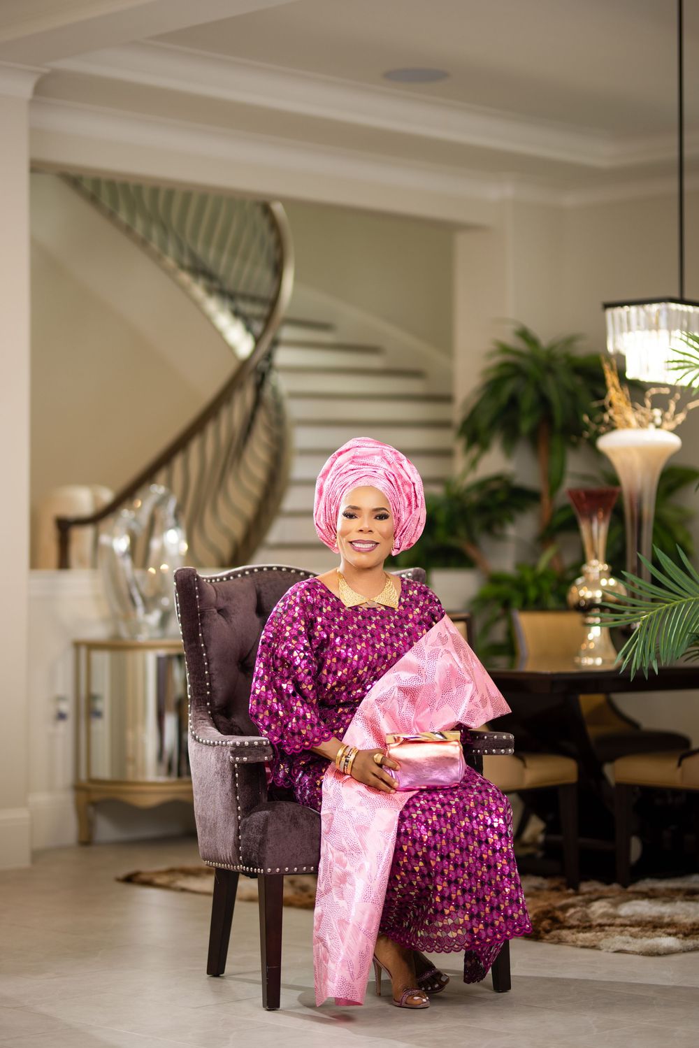 Traditional African fashion displayed in elegant indoor setting with plush purple chairs and warm lighting.