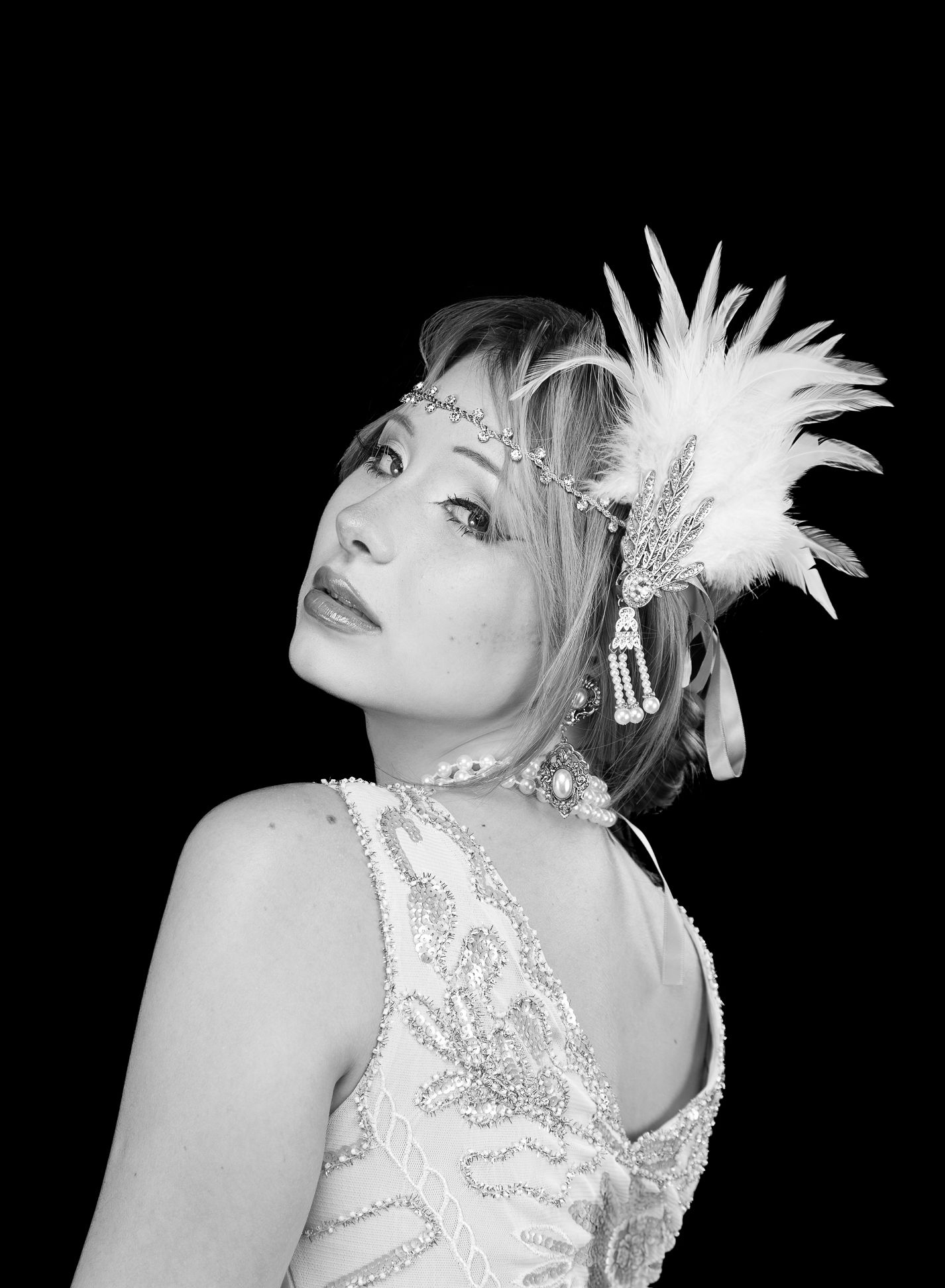 Black and white photo of a girl in a flapper costume, looking direct centre