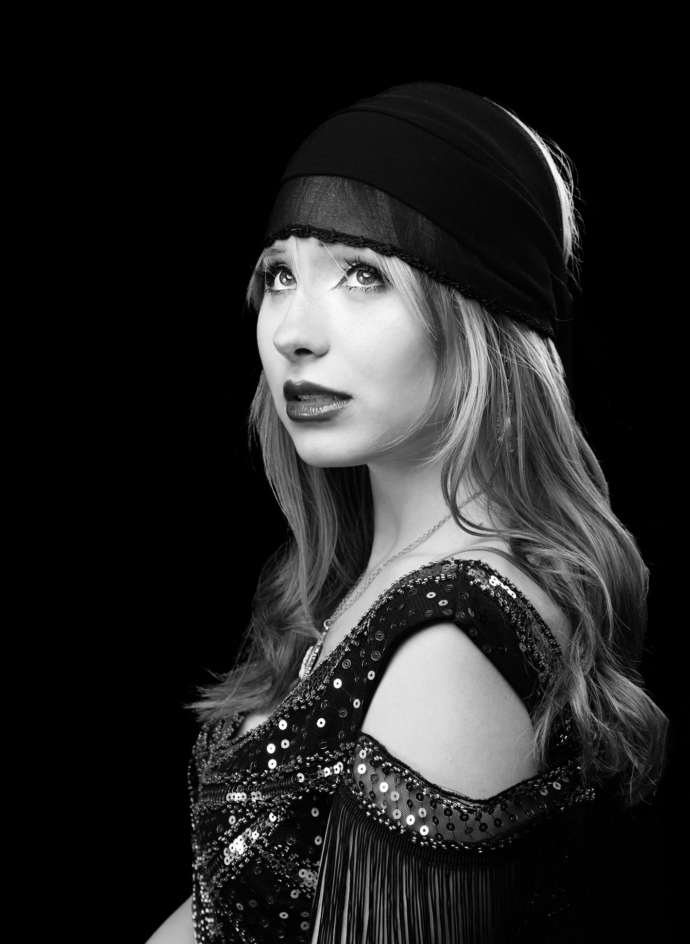 Black and white photo of a girl with a headscarf on, looking up and left