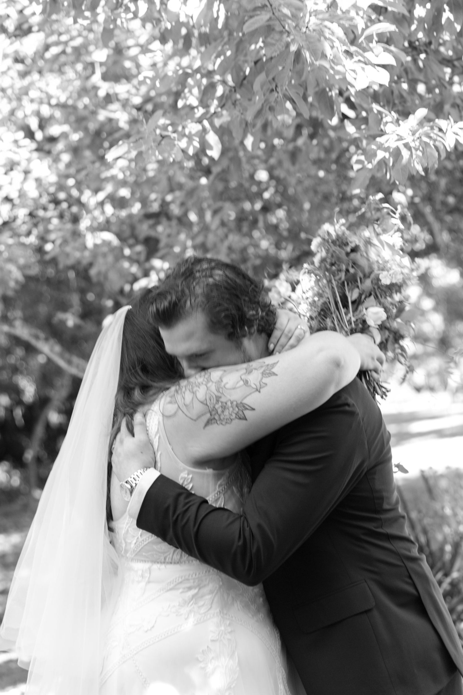 A romantic black and white wedding photo series showing a couple embracing and kissing outdoors.