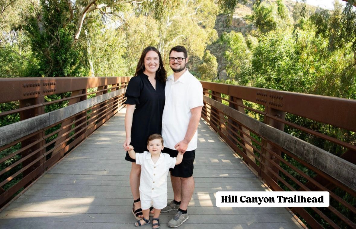 A family stands together on a wooden bridge at Hill Canyon Trailhead surrounded by lush greenery.
