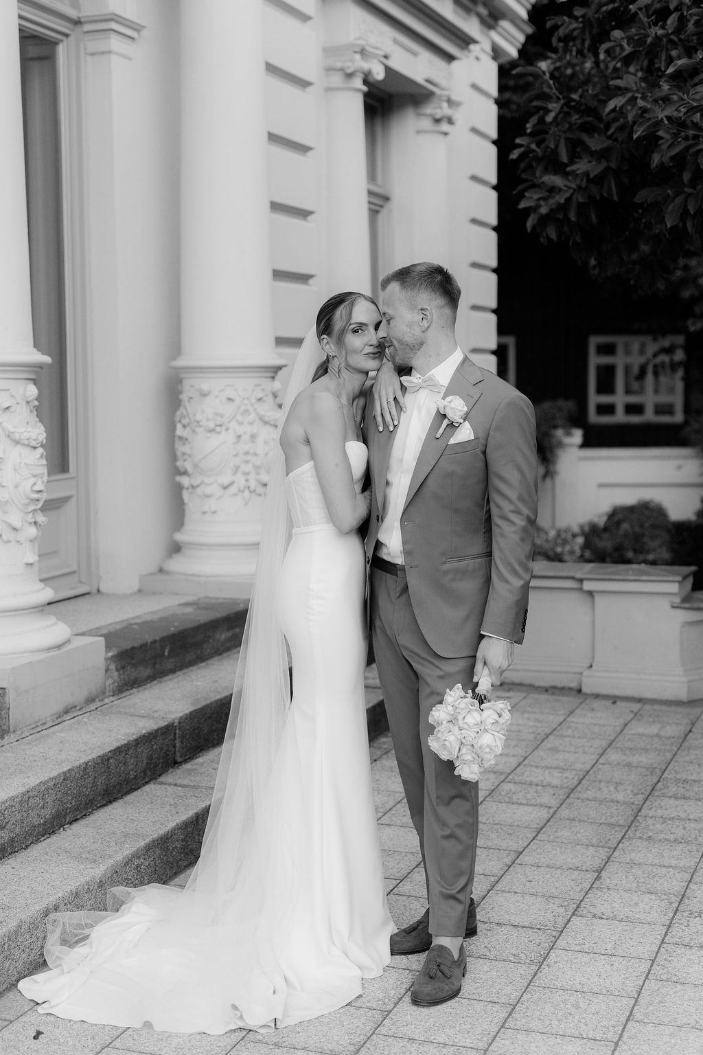 Romantic wedding couple shares intimate moments in a series of black and white photos against a classic white building.