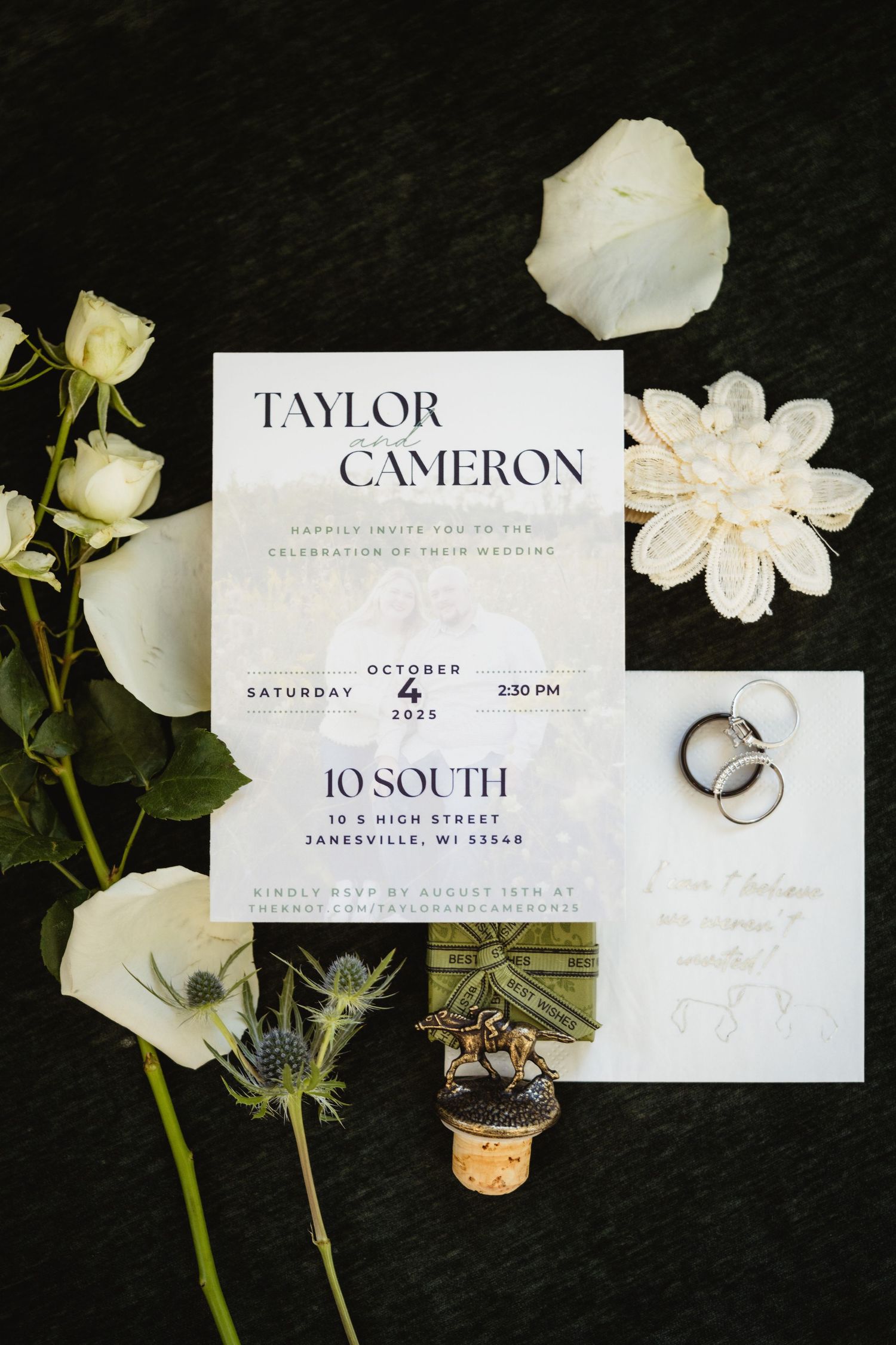Elegant wedding invitation suite with white flowers and rings displayed on dark background with modern typography.