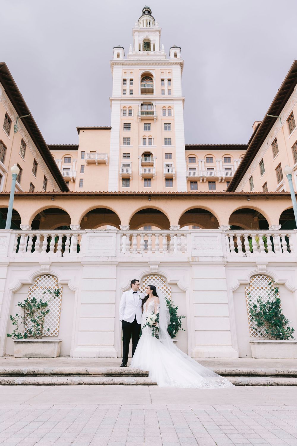 Wedding photography session at a grand Mediterranean-style building with arches.