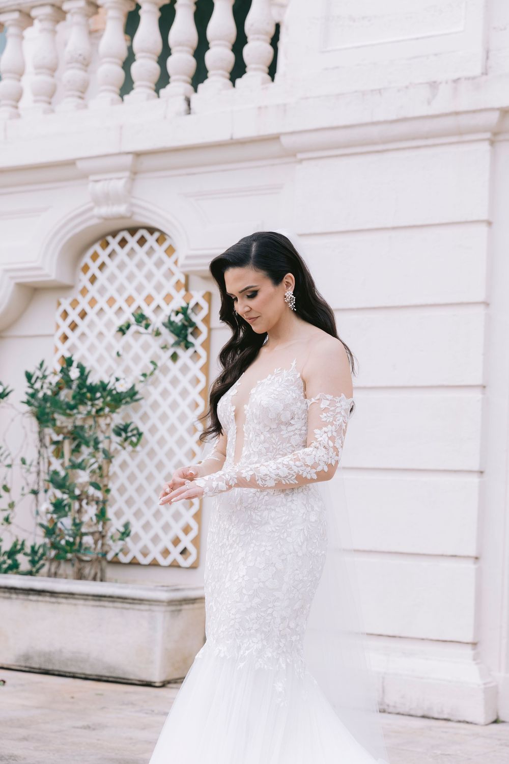 Dancing bride in flowing lace dress against classical white architecture.