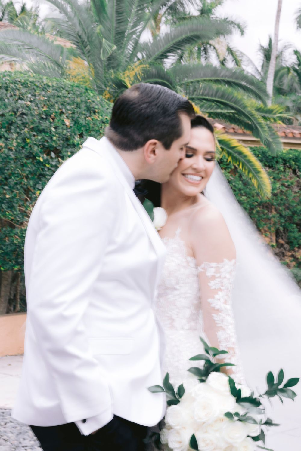 Romantic wedding portraits with palm trees and greenery in the background.