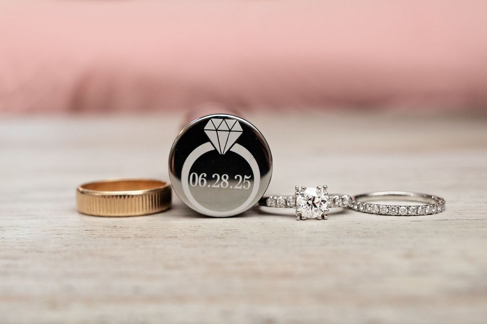 Close-up view of elegant wedding rings and engagement ring with diamonds arranged on light textured surface.