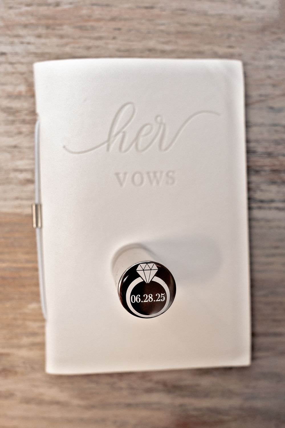 White wedding vow books with elegant calligraphy and a diamond ring icon displayed on a wooden surface.