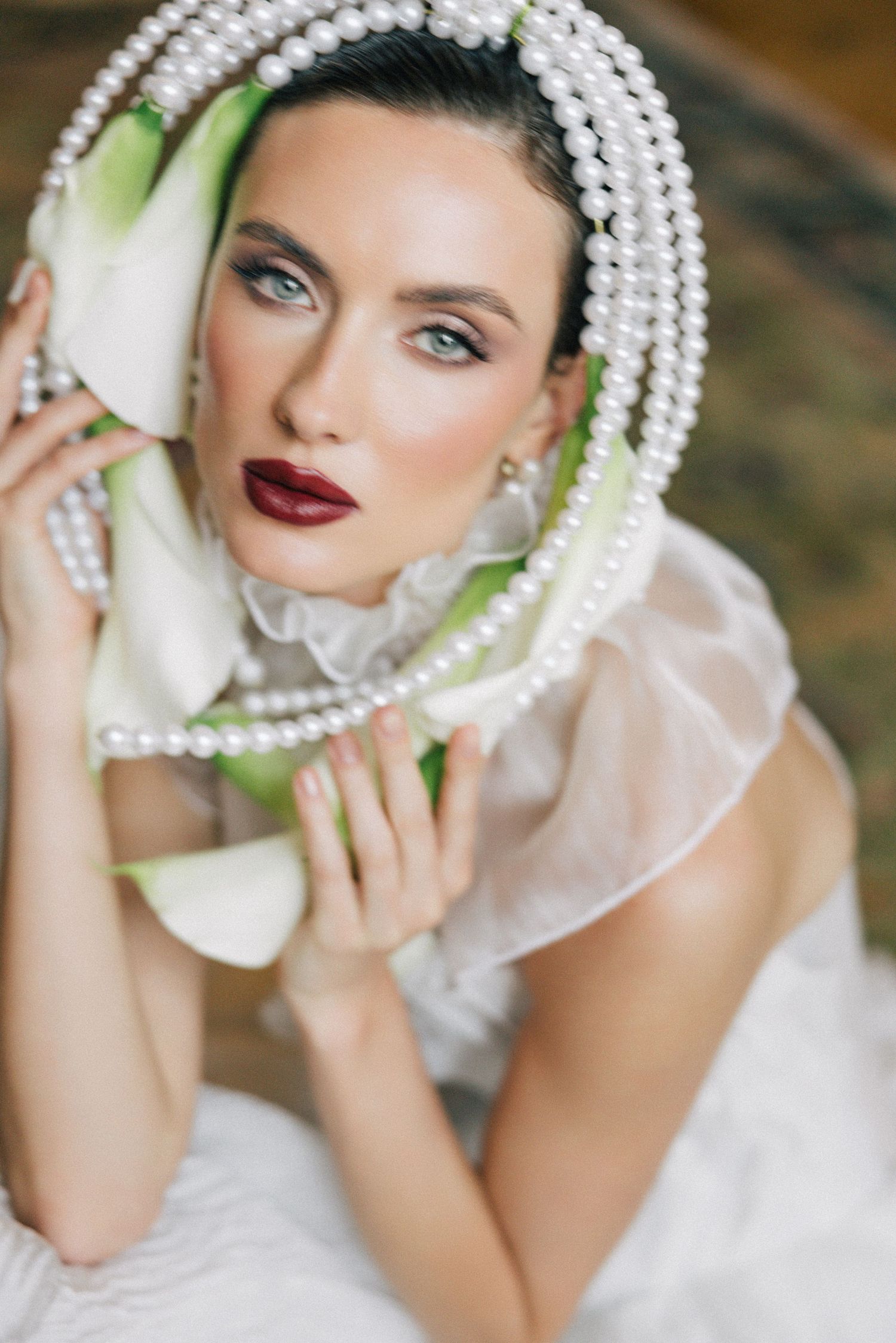A glamorous bridal portrait featuring pearl necklaces and a white dress with elegant vintage-inspired styling.