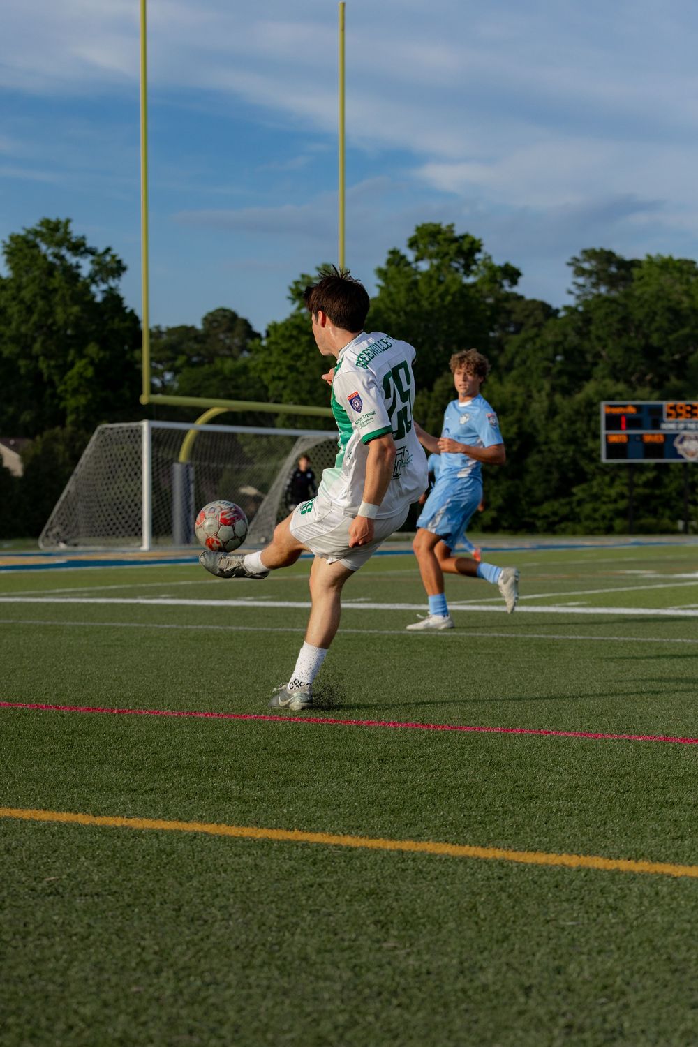 Young soccer player in white uniform controls the ball during a youth match on a turf field.