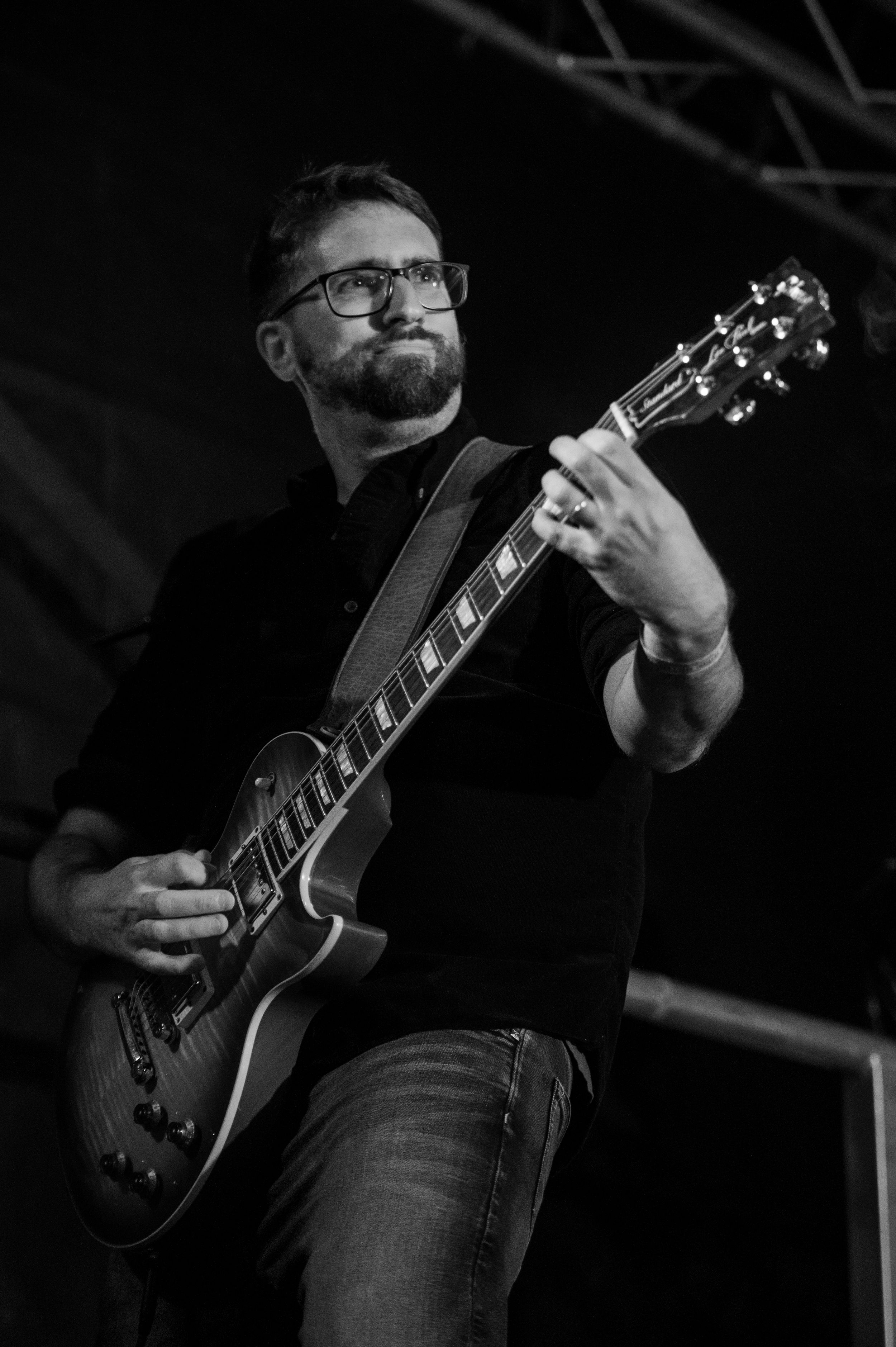 Black and white close-up photos of a guitarist playing an electric guitar during a performance.