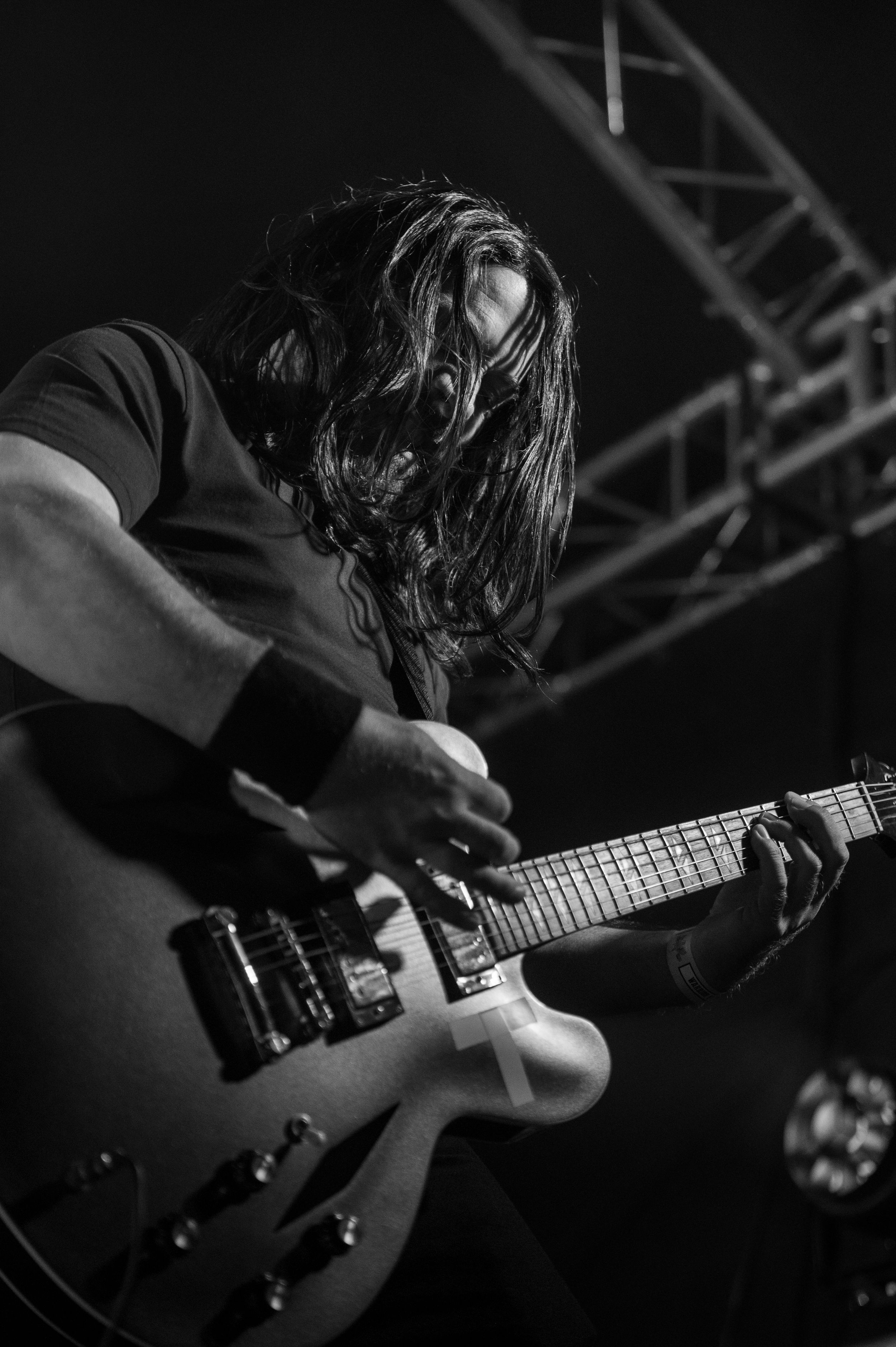 Close-up black and white shots of a guitarist playing an electric guitar during a live performance.