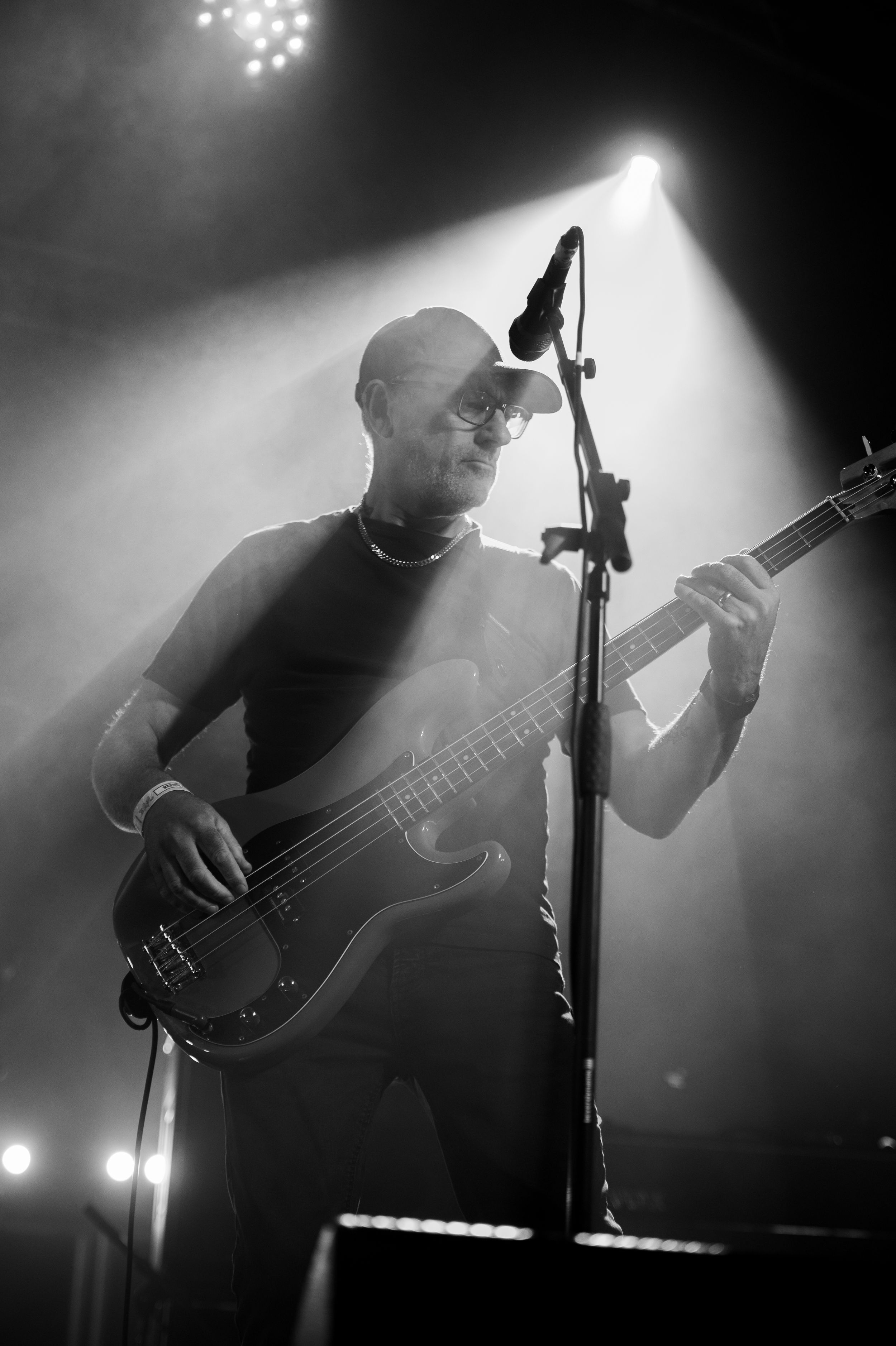 A moody black and white photo series of a bass guitarist performing on stage with dramatic lighting and fog effects.