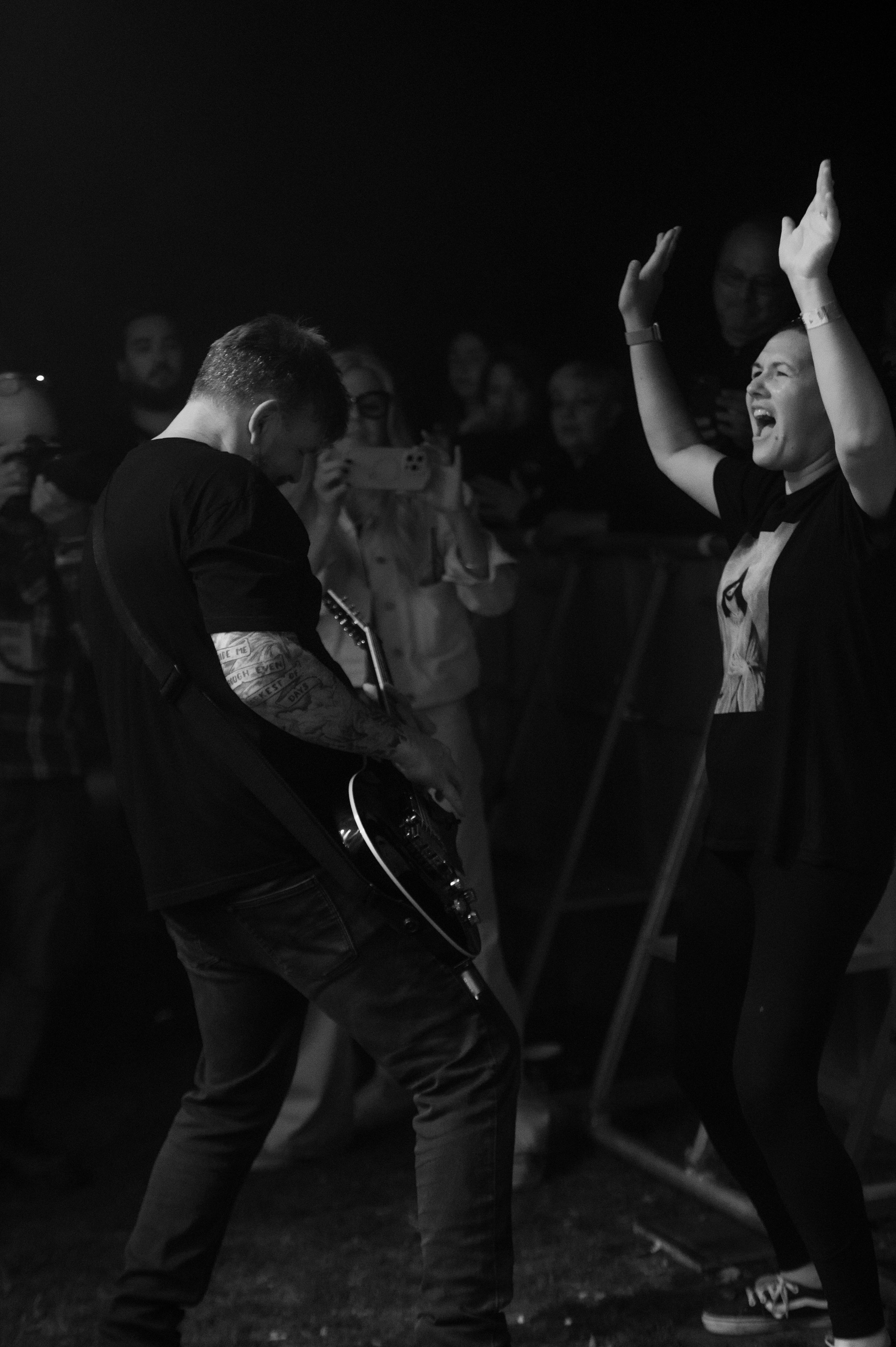 Black and white photo of a crowded dance floor showing people's legs and feet dancing in a dark nightclub setting.