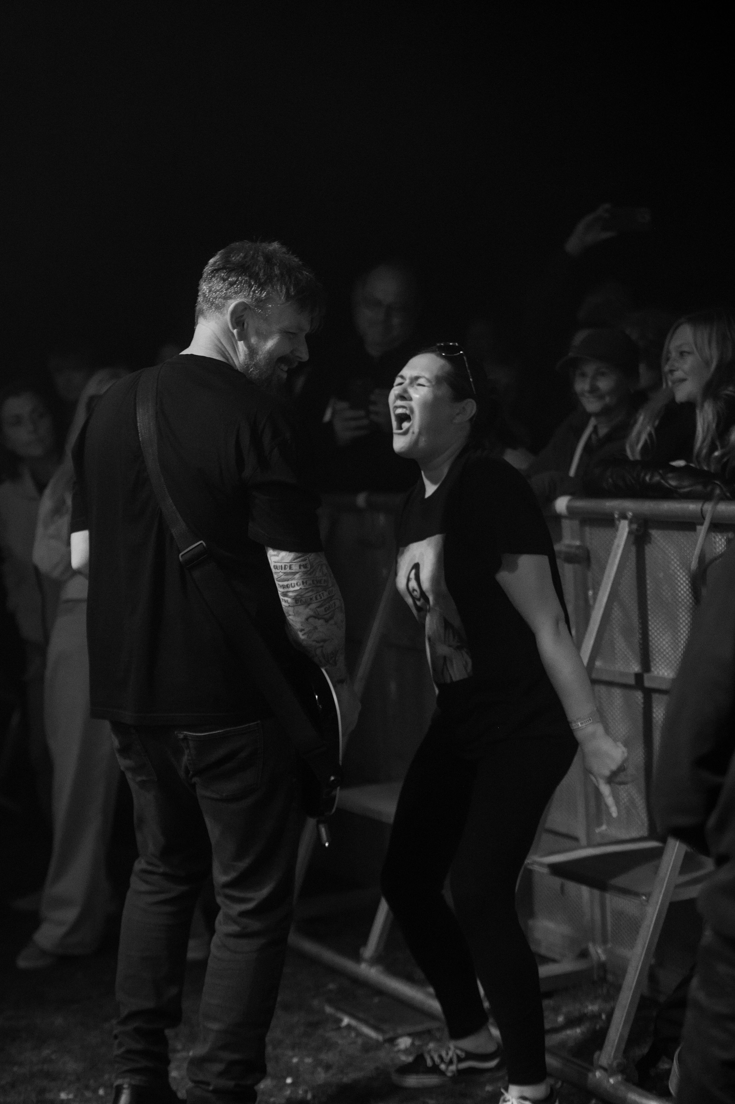 Black and white photo of a concert crowd watching performers on stage in a dark venue.
