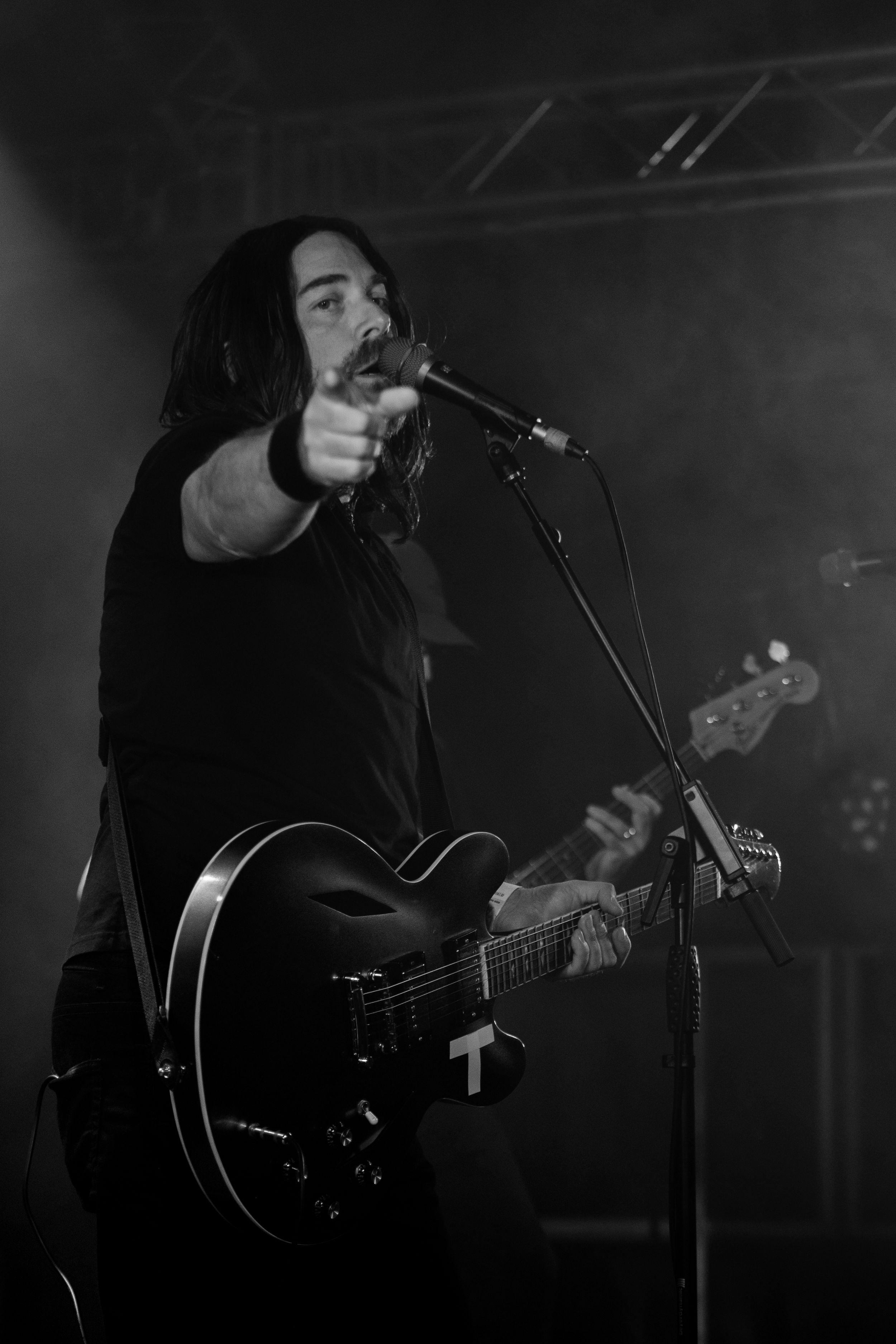 A series of black and white photos showing a musician performing with a guitar in atmospheric stage lighting.