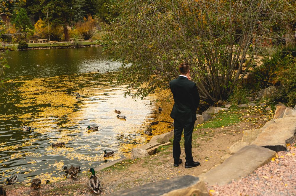 A scenic autumn park path along a pond with golden reflections in the water during sunset.