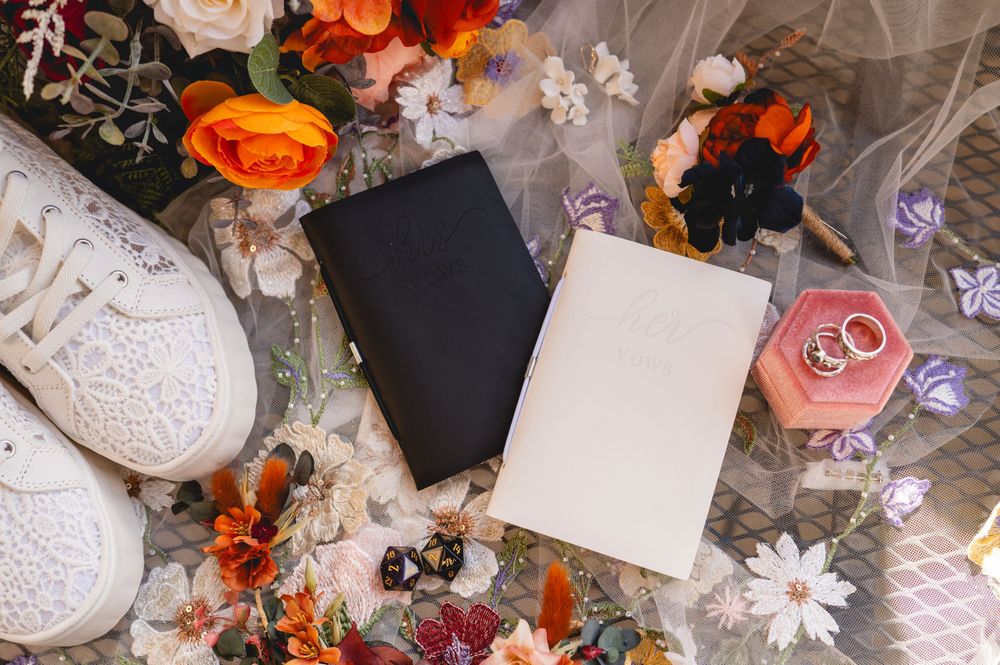 Flat lay with blank black and white cards surrounded by orange roses, lace details and scattered floral decorations.