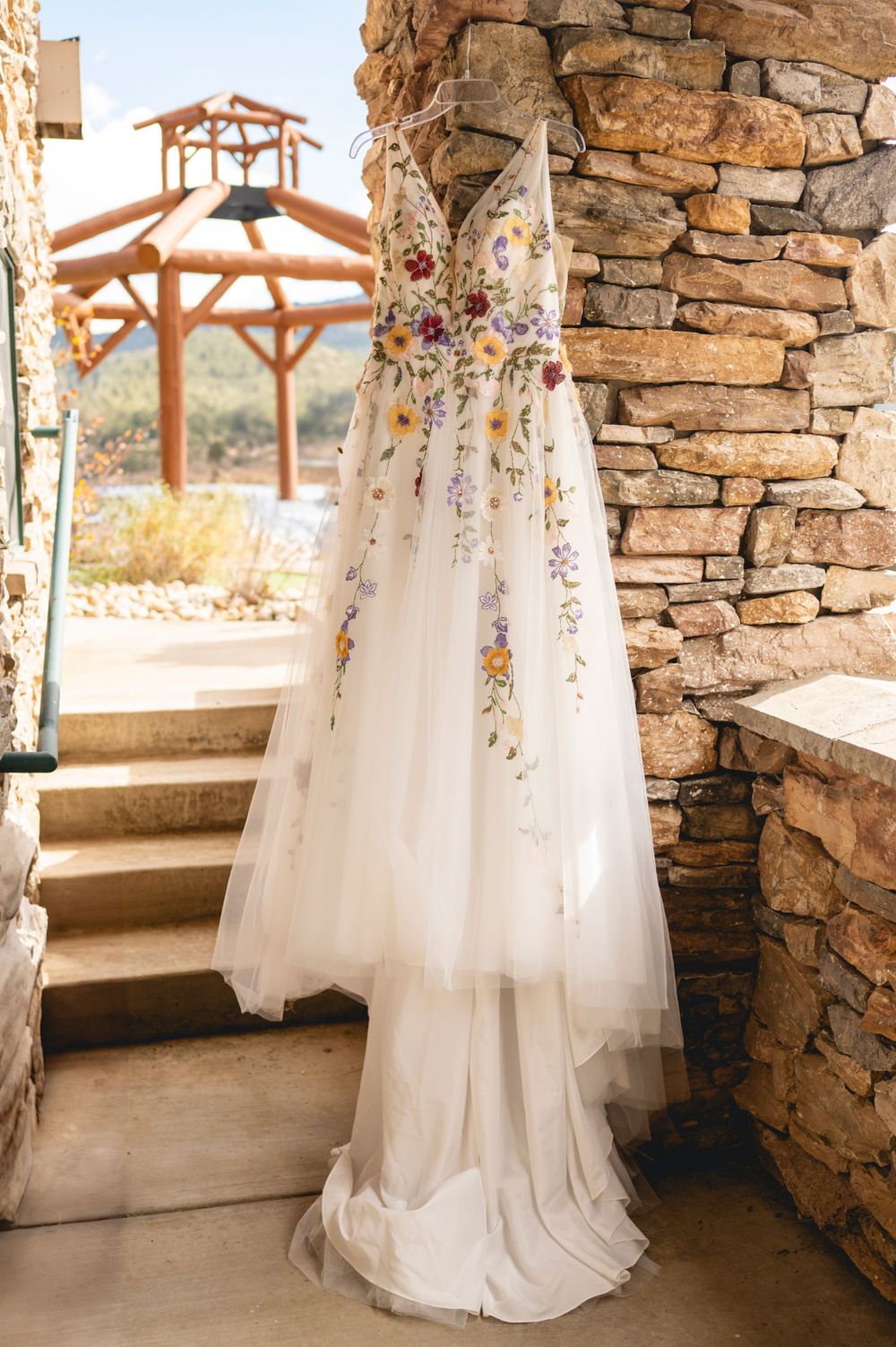 White wedding dresses hanging from stone archways in a rustic venue with natural light streaming through windows.